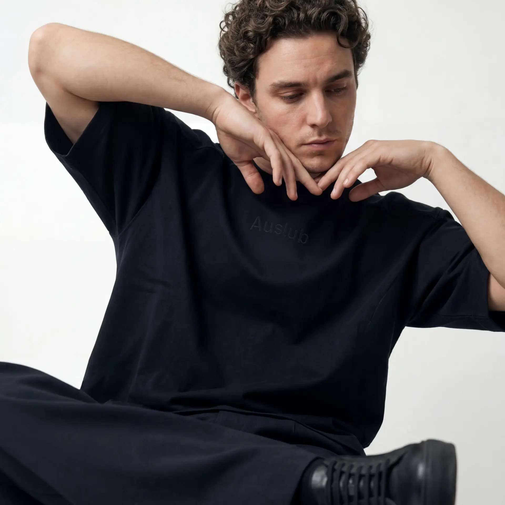 AUSLUB campaign portrait — model in a black oversized tee with tonal Auslub print