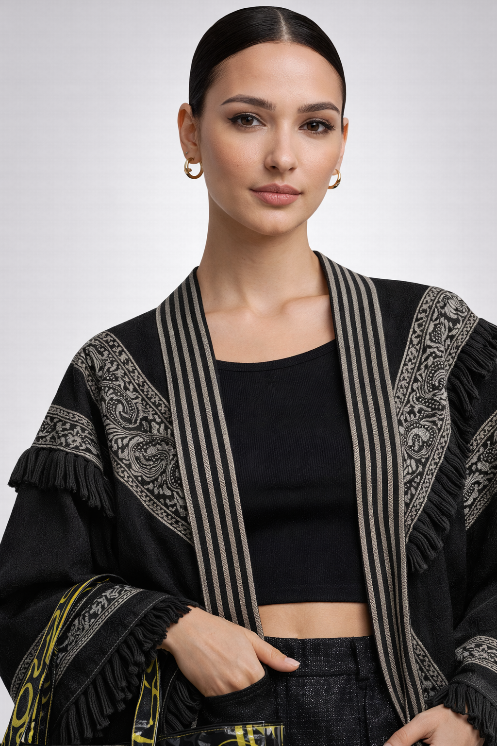 Model in a black embroidered jacket with structured lapels and gold hoop earrings
