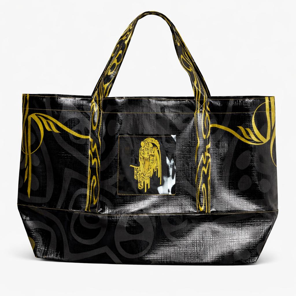 Tote bag front view — black coated canvas with gold motif print and patterned handles